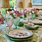 Elegant dining table setting with floral plates, glasses, and centerpieces.