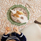 Golden velvet bow napkin ties styled for a Thanksgiving table setting with brown floral china and green scalloped placemats from Henry Duvall.
