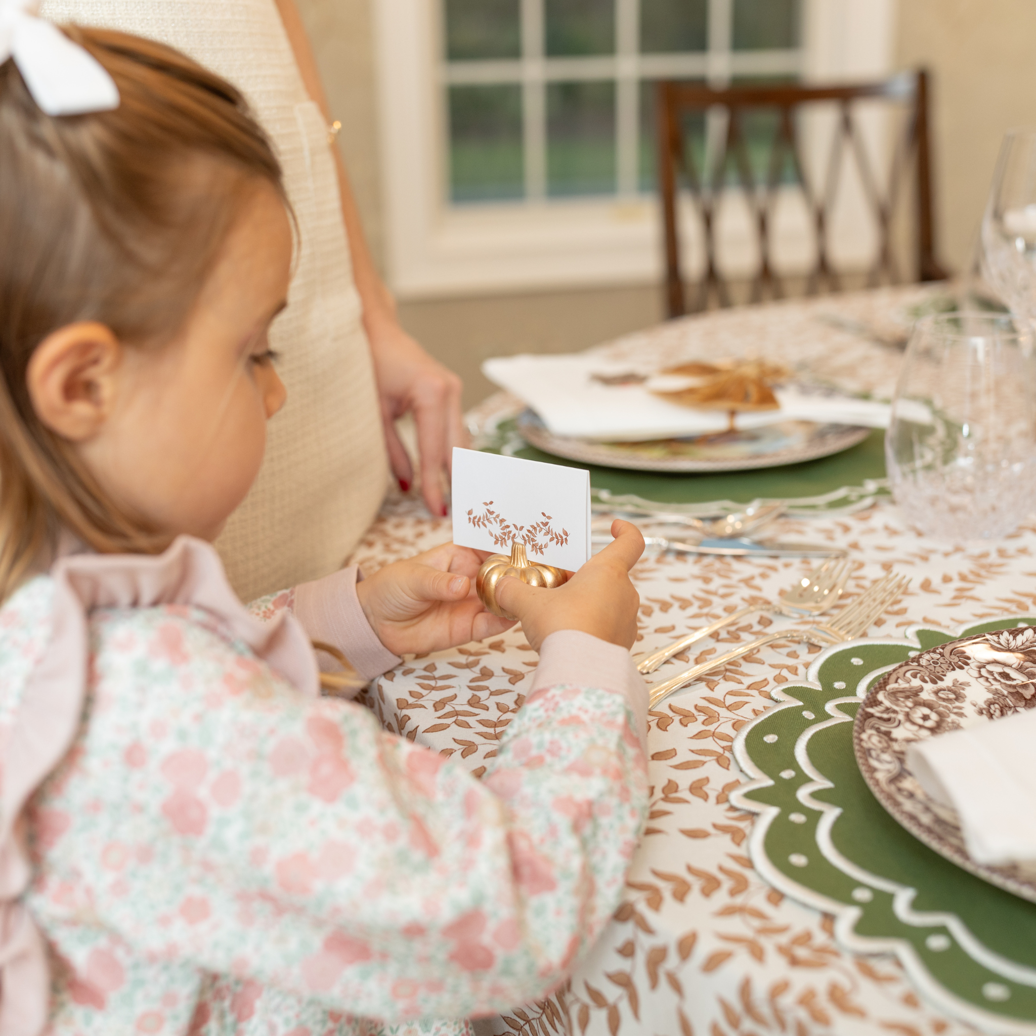 Folded tent-style Thanksgiving place cards with brown woodland leaf motif, matching fall tablecloths and Thanksgiving tabletop decor