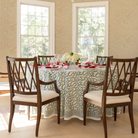 Holiday tablescape with Flying Sheep Country green leaf block-printed tablecloth, red ribbon details, holiday crackers, crystal glassware, and a white floral centerpiece