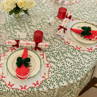 Red cloth napkin with white scalloped edge and embroidered dot detailing, styled for a festive holiday table setting.