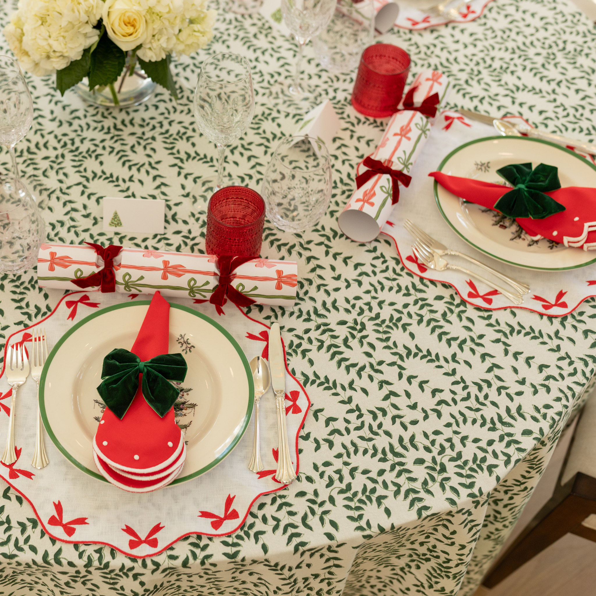 Red cloth napkin with white scalloped edge and embroidered dot detailing, styled for a festive holiday table setting.