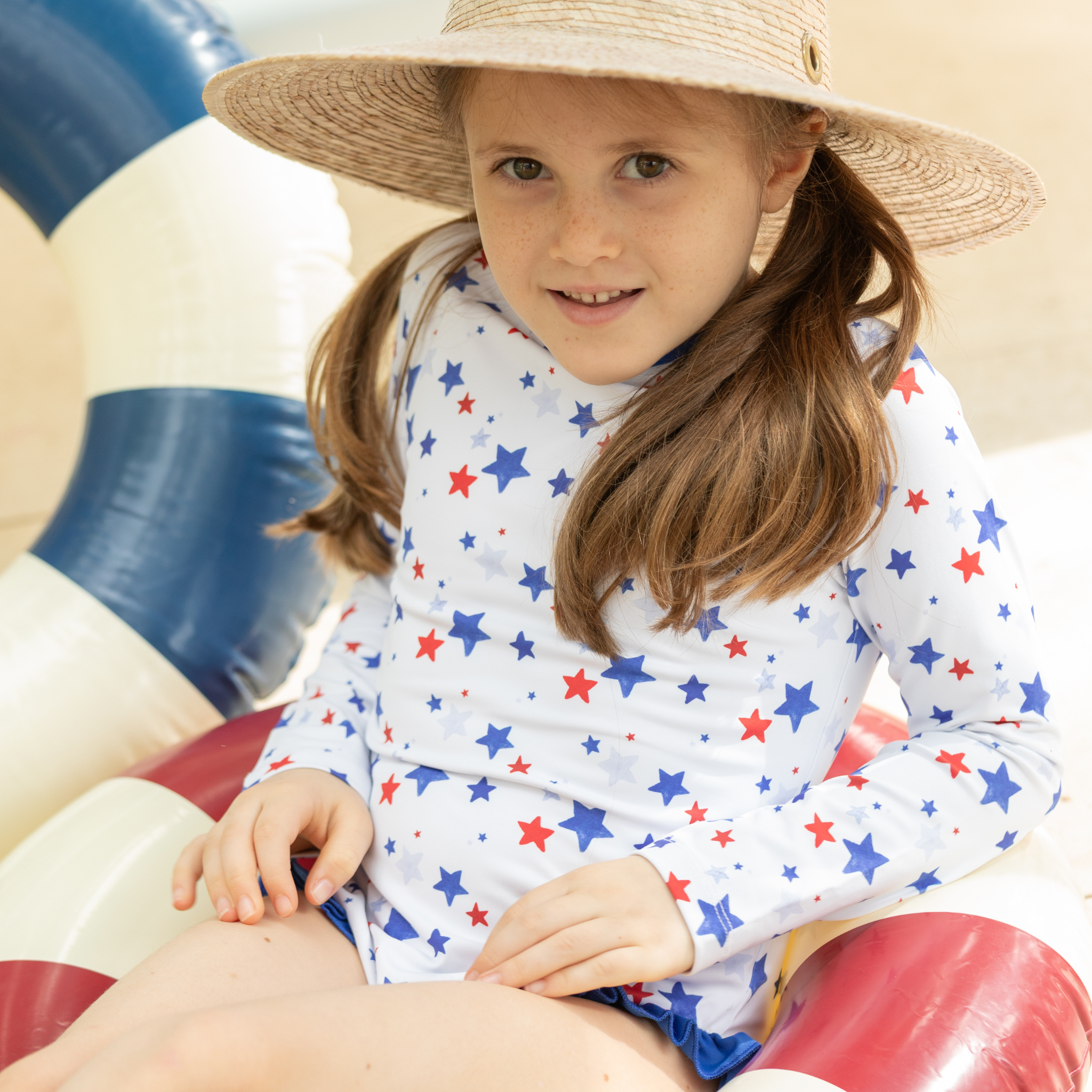 Henry Duvall Reese girls rashguard one piece in red white and blue star print, UPF 50+ long sleeve swimsuit for 4th of July, beach, and summer holidays