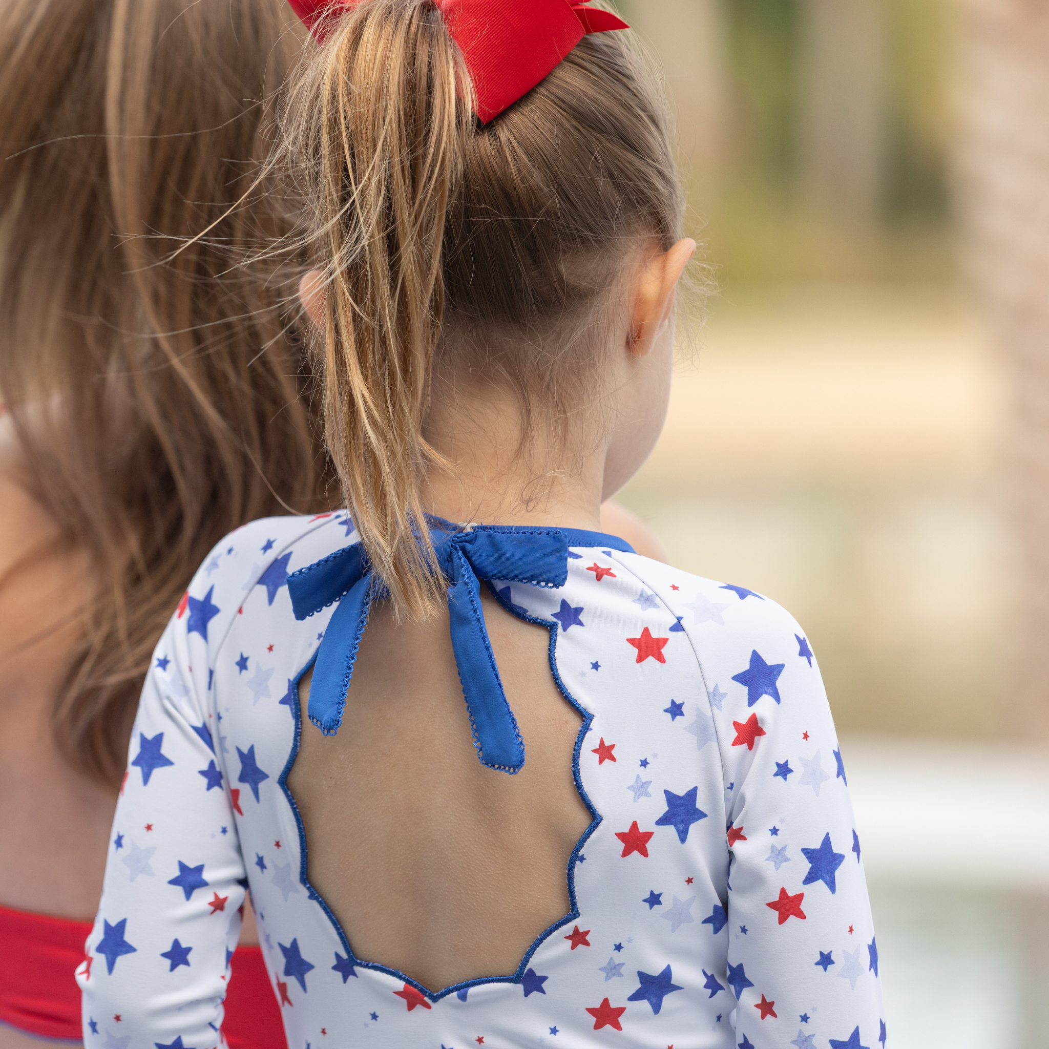 Henry Duvall Reese girls rashguard one piece in red white and blue star print, UPF 50+ long sleeve swimsuit for 4th of July, beach, and summer holidays
