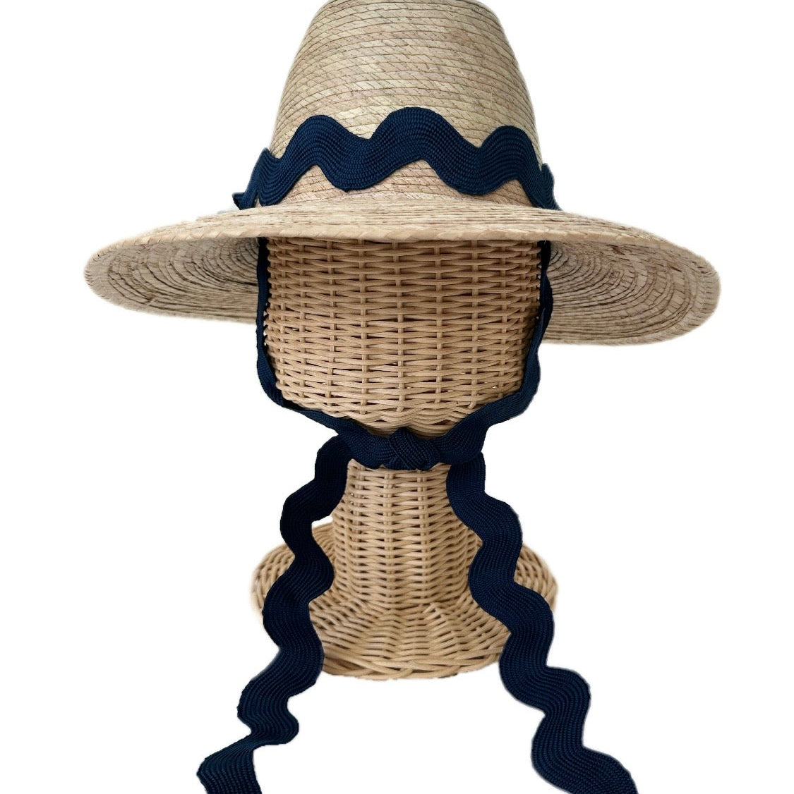 Woven sun hat with navy blue ribbon on a mannequin head against a white background
