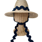 Woven sun hat with navy blue ribbon on a mannequin head against a white background
