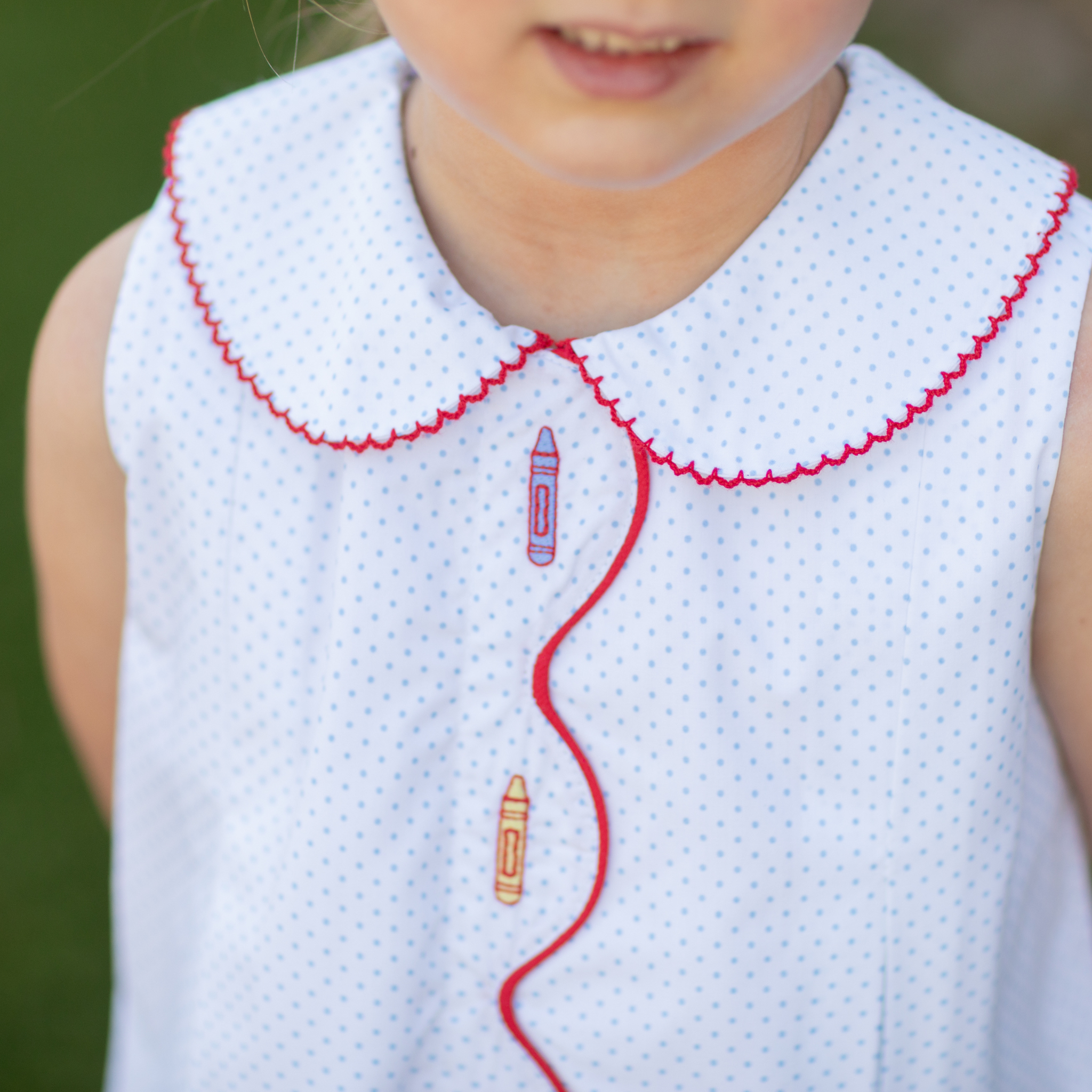 Henry Duvall Lucy Dress in blue micro dot cotton featuring a Peter Pan collar, red scalloped trim, and embroidered crayons, classic girls back-to-school dress for first day of school photos and classroom celebrations.