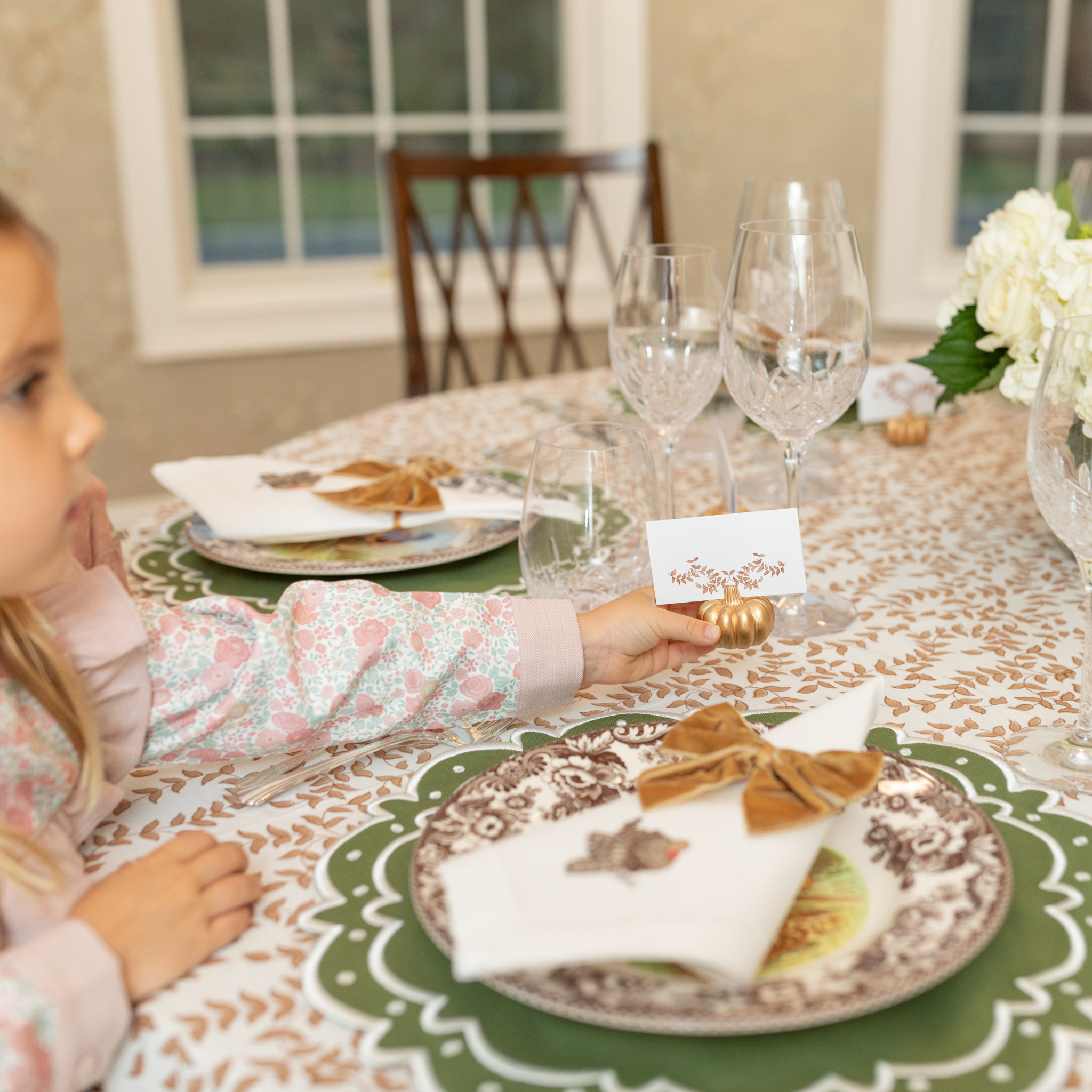 Folded tent-style Thanksgiving place cards with brown woodland leaf motif, matching fall tablecloths and Thanksgiving tabletop decor