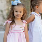 Henry Duvall Daisy Dress in blush pink cotton with hand-smocked crayon embroidery and shoulder bow ties, classic girls back-to-school dress for first day of school photos and fall occasions.