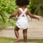 Henry Duvall unisex baby sunsuit in white with red and blue star appliqué and criss cross straps, classic patriotic outfit for Memorial Day, 4th of July, and summer occasions