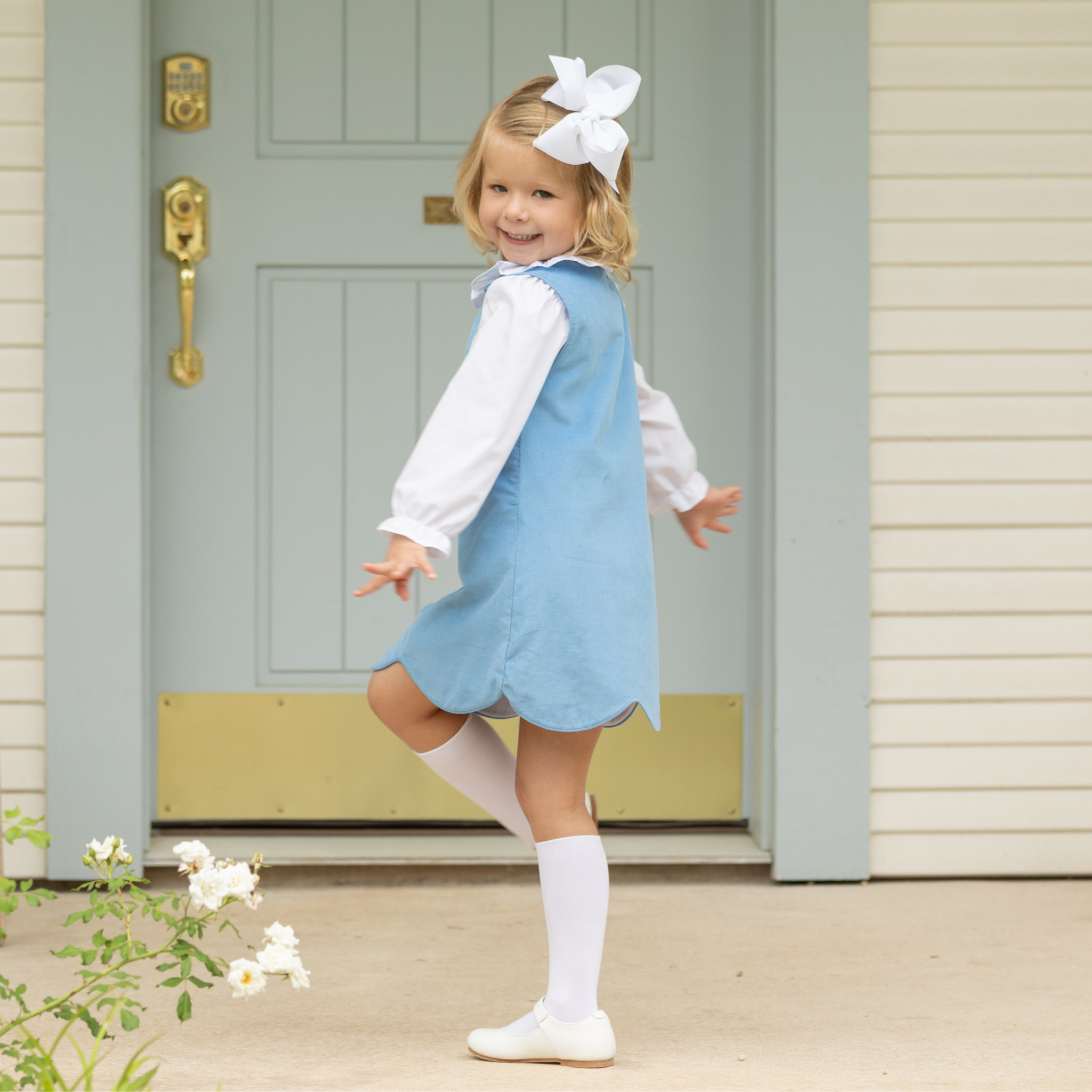 Henry Duvall Janie Jumper girls’ dress in Brookhaven Blue corduroy with scalloped hem and fabric-covered shoulder buttons, designed for layering with blouses and turtlenecks for fall.