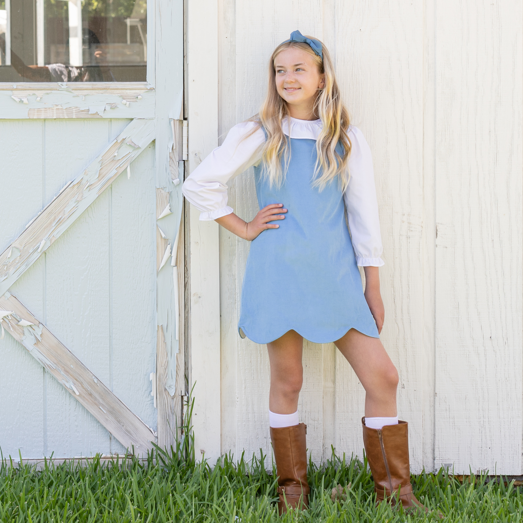 Henry Duvall Janie Jumper girls’ dress in Brookhaven Blue corduroy with scalloped hem and fabric-covered shoulder buttons, designed for layering with blouses and turtlenecks for fall.