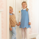 Henry Duvall Janie Jumper girls’ dress in Brookhaven Blue corduroy with scalloped hem and fabric-covered shoulder buttons, designed for layering with blouses and turtlenecks for fall.