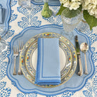 Elegant table setting with blue and white patterns, silverware, and a floral centerpiece.