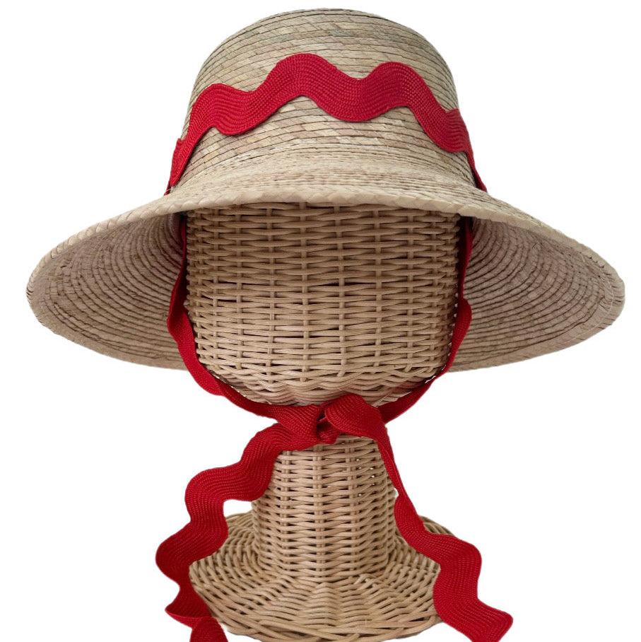 Woven sun hat with red ribbon on a mannequin head against a white background