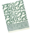 Holiday tablescape with Flying Sheep Country green leaf block-printed tablecloth, red ribbon details, holiday crackers, crystal glassware, and a white floral centerpiece