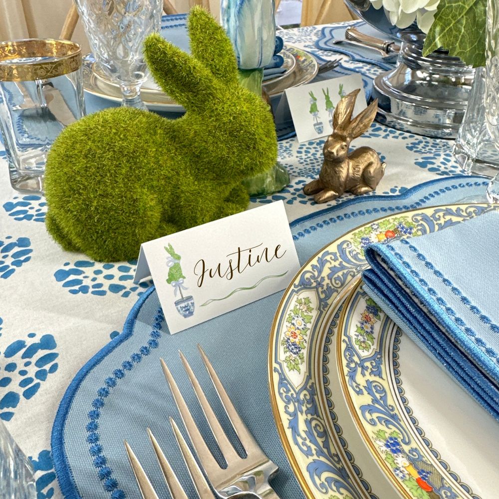 Easter table setting with decorative bunnies, place card, and patterned plates.