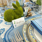 Easter table setting with decorative bunnies, place card, and patterned plates.