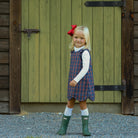 Henry Duvall Janie Jumper girls’ holiday dress in Tinsel Tartan, a navy, red and green plaid with subtle gold metallic thread, scalloped hem, navy piping and gold shoulder buttons.