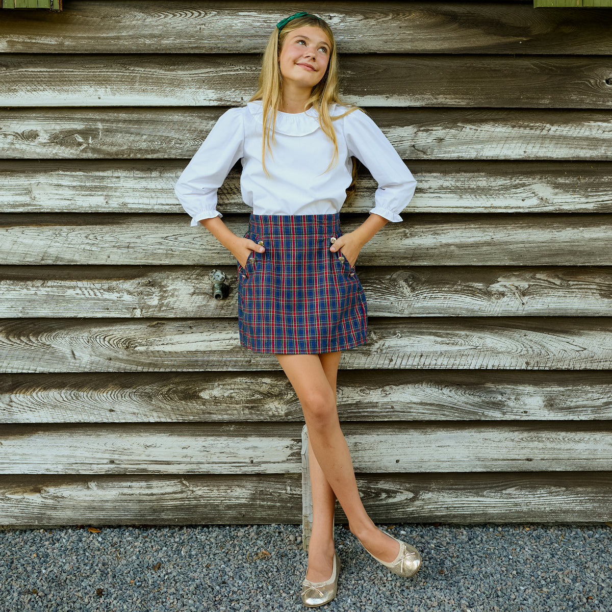 Girls’ Sadie Skirt in navy, red, and green Tinsel Tartan with subtle metallic thread, HD gold buttons, flat front, and A-line silhouette.