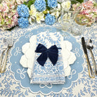 Decorative table setting with blue and white floral patterns, a navy bow, and silverware.