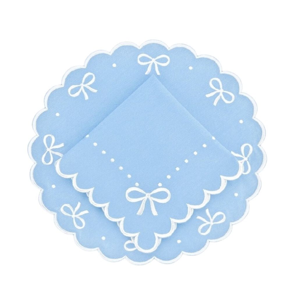 Light blue doily with white scalloped edges and bow designs on a white background