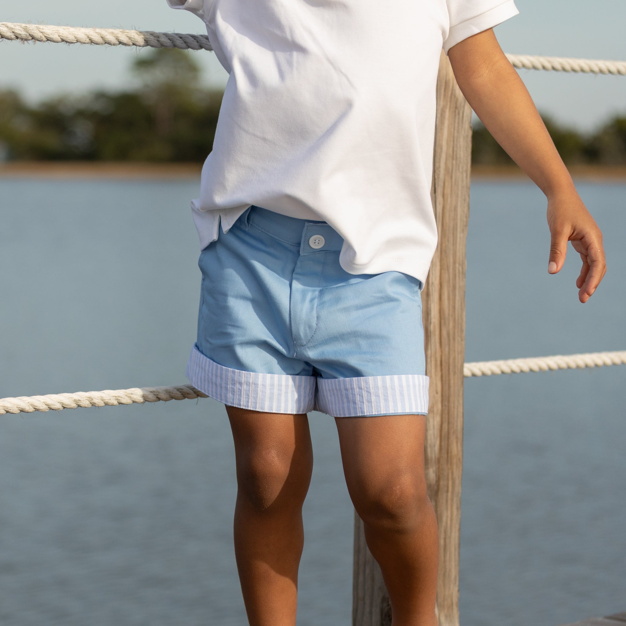 Boy wearing Henry Duvall Wyatt Shorts in East Beach Blue with striped cuffs, a classic boys short styled for spring days and timeless family moments