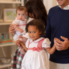 White short sleeve baby girl holiday bubble with red smocked bows, Peter Pan collar, and piped cuffs, classic Eloise Bubble by Henry Duvall for Christmas and winter celebrations