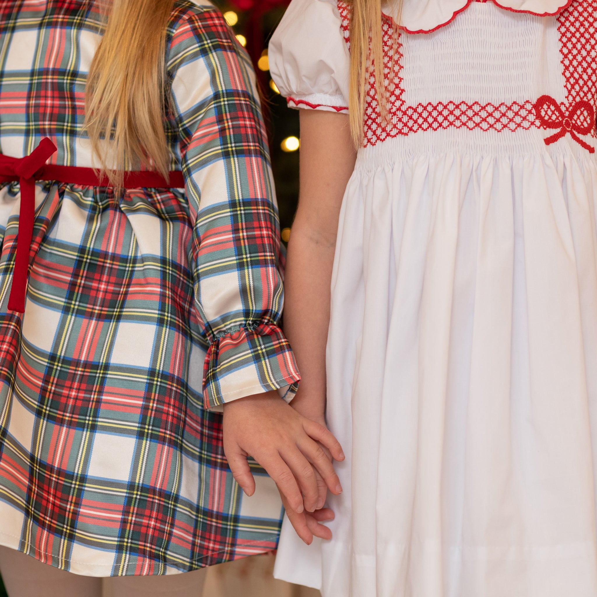 White short sleeve girls' holiday dress with red bow smocking across the chest, Peter Pan collar, and piped cuffs, classic Henry Duvall Eloise Dress for Christmas and winter family gatherings