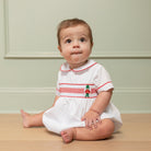 White baby boy holiday bubble with red toy soldier smocking and Peter Pan collar, Henry Duvall's Charlie Bubble in cotton poplin for Christmas celebrations
