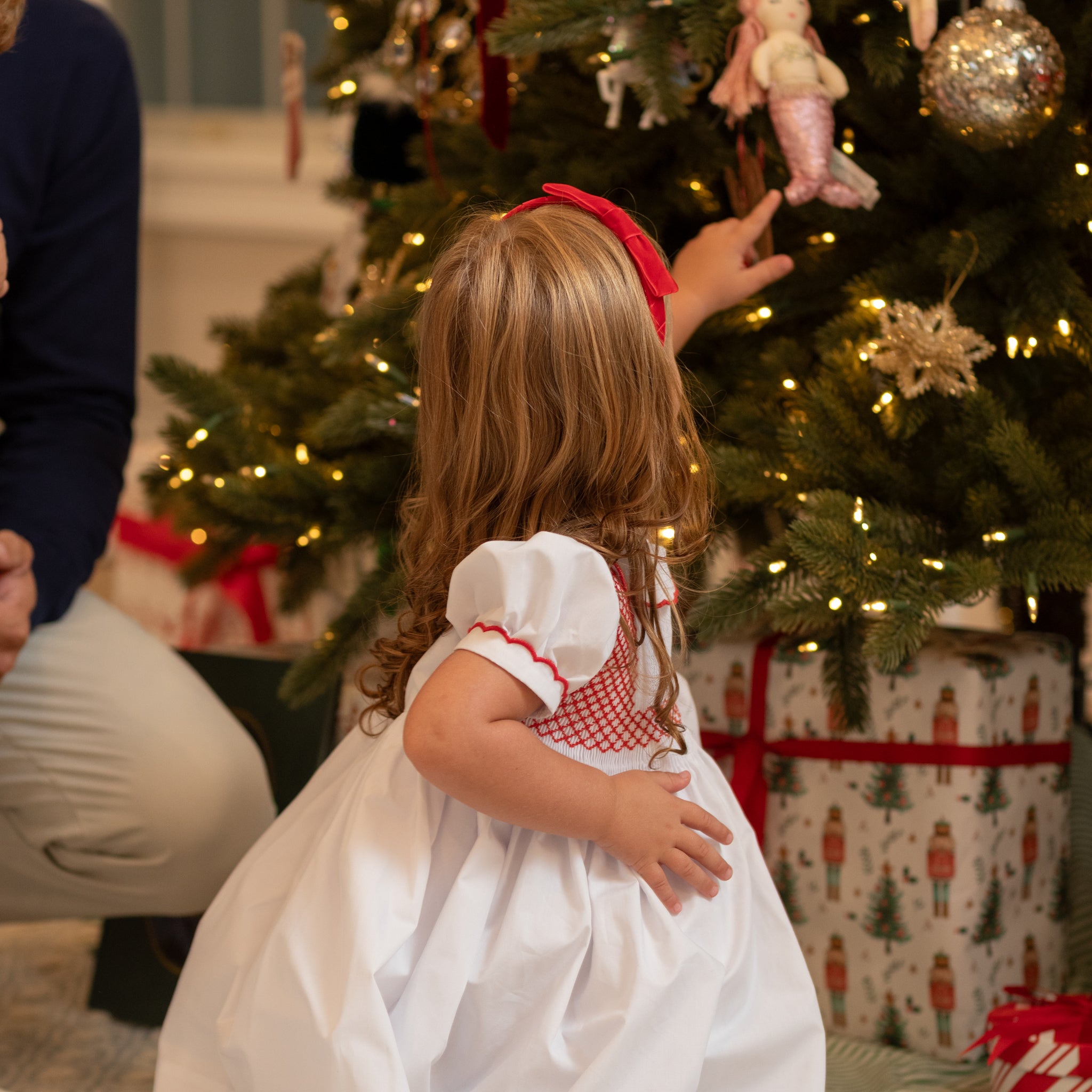 White short sleeve girls' holiday dress with red bow smocking across the chest, Peter Pan collar, and piped cuffs, classic Henry Duvall Eloise Dress for Christmas and winter family gatherings