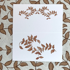 Folded tent-style Thanksgiving place cards with brown woodland leaf motif, matching fall tablecloths and Thanksgiving tabletop decor