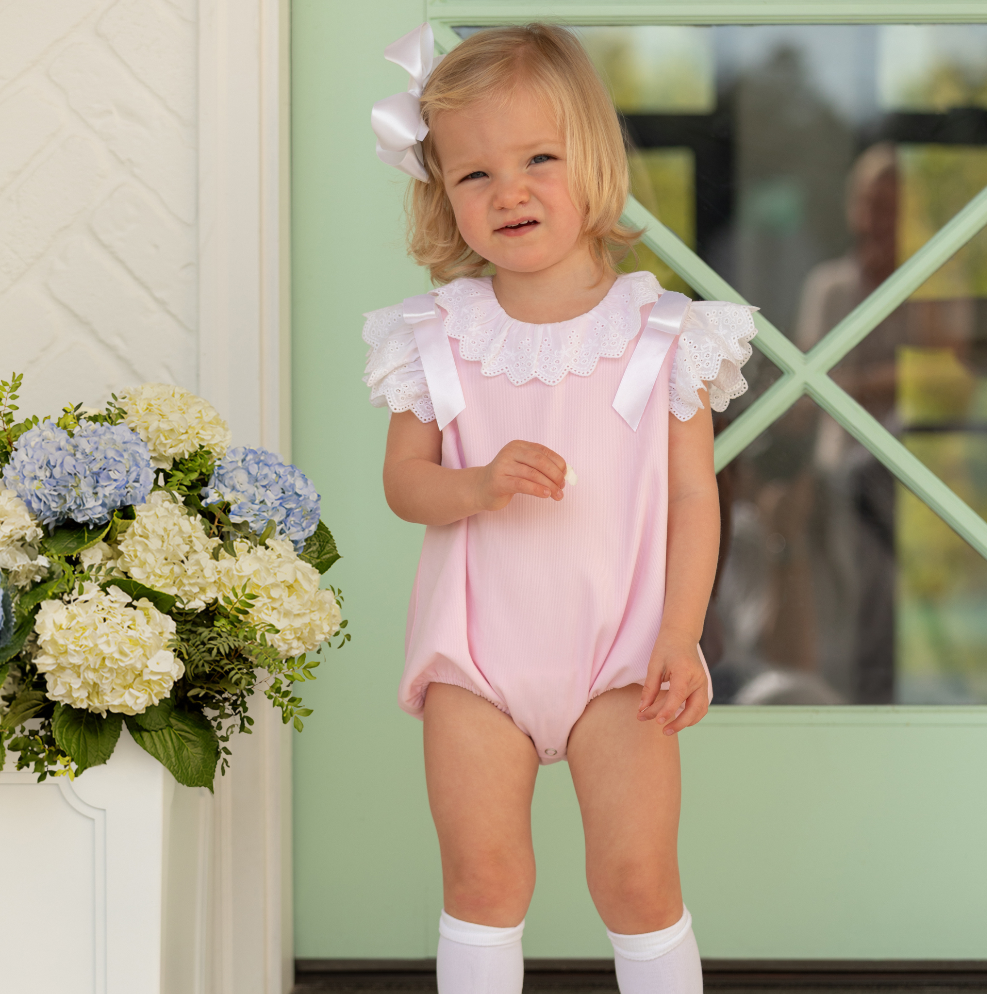 Toddler girl wearing the Henry Duvall Rosie Bubble, a classic pink bubble designed for spring days and special moments.