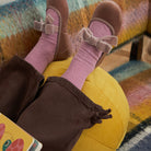 Andie Rose velvet Mary Jane in rose pink with velvet bow, worn by child resting on a yellow pouf