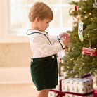 Boys’ Benjamin Button On with crisp white long-sleeve cotton poplin top, Grafton Green piping and pintuck details, paired with Grafton Green Velvet shorts and signature HD buttons.