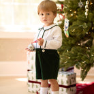 Boys’ Benjamin Button On with crisp white long-sleeve cotton poplin top, Grafton Green piping and pintuck details, paired with Grafton Green Velvet shorts and signature HD buttons.