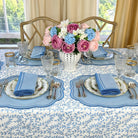 Elegant table setting with floral centerpiece, blue and white tablecloth, and silverware.