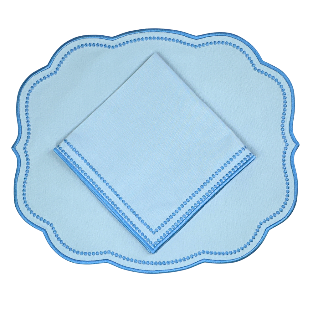 Light blue scalloped placemat with matching napkin on a white background