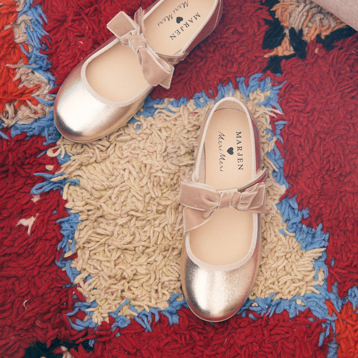 Meri Meri x Marjen Missy metallic gold Mary Jane with velvet bow, pair on a red rug