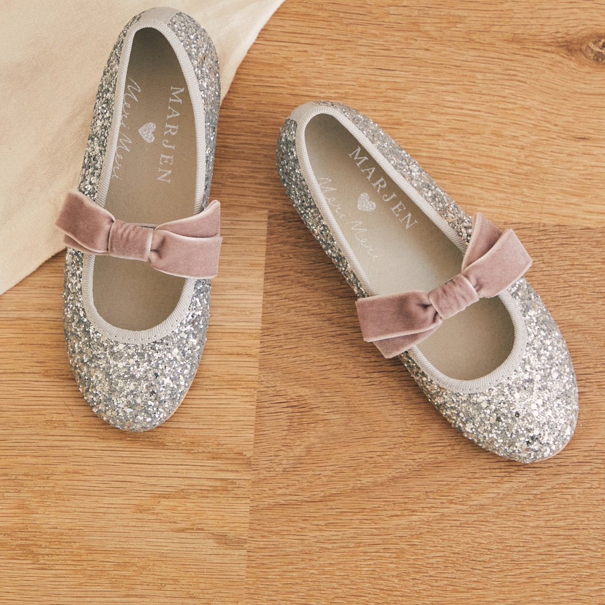 Meri Meri x Marjen Sabrina silver glitter Mary Jane with rose velvet bow, pair on a wood floor