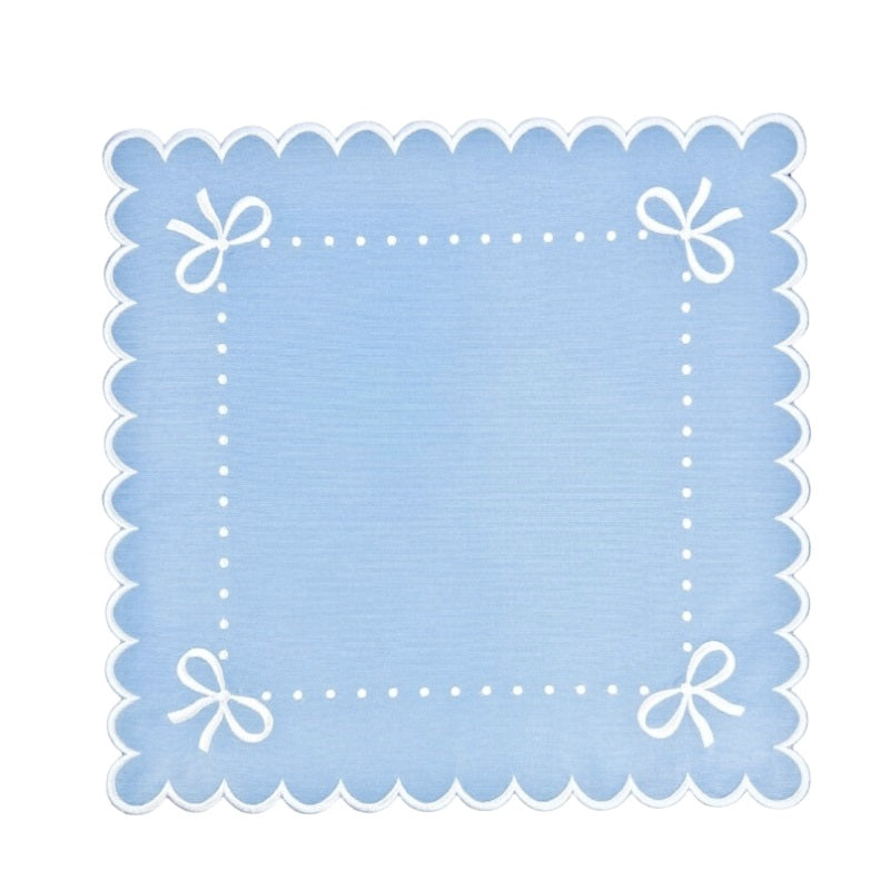 Light blue placemat with white scalloped edge and decorative bows on a white background