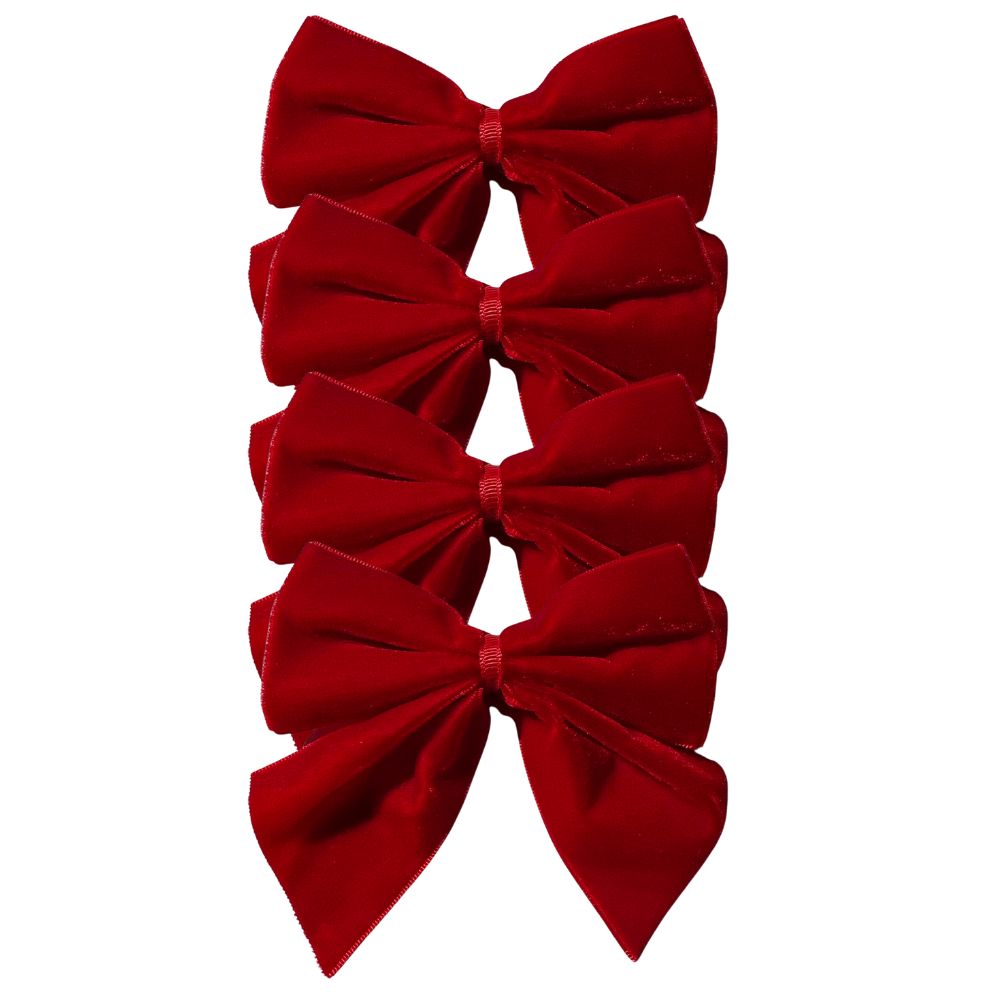 Red velvet bow napkin ties on white napkins, styled on a festive holiday table with holly tablecloth and scalloped placemats – perfect for Christmas entertaining and seasonal celebrations.