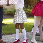Girls’ Sutton Skirt in Regent Wreaths, featuring a festive green wreath and red star print on white with a full gathered silhouette.