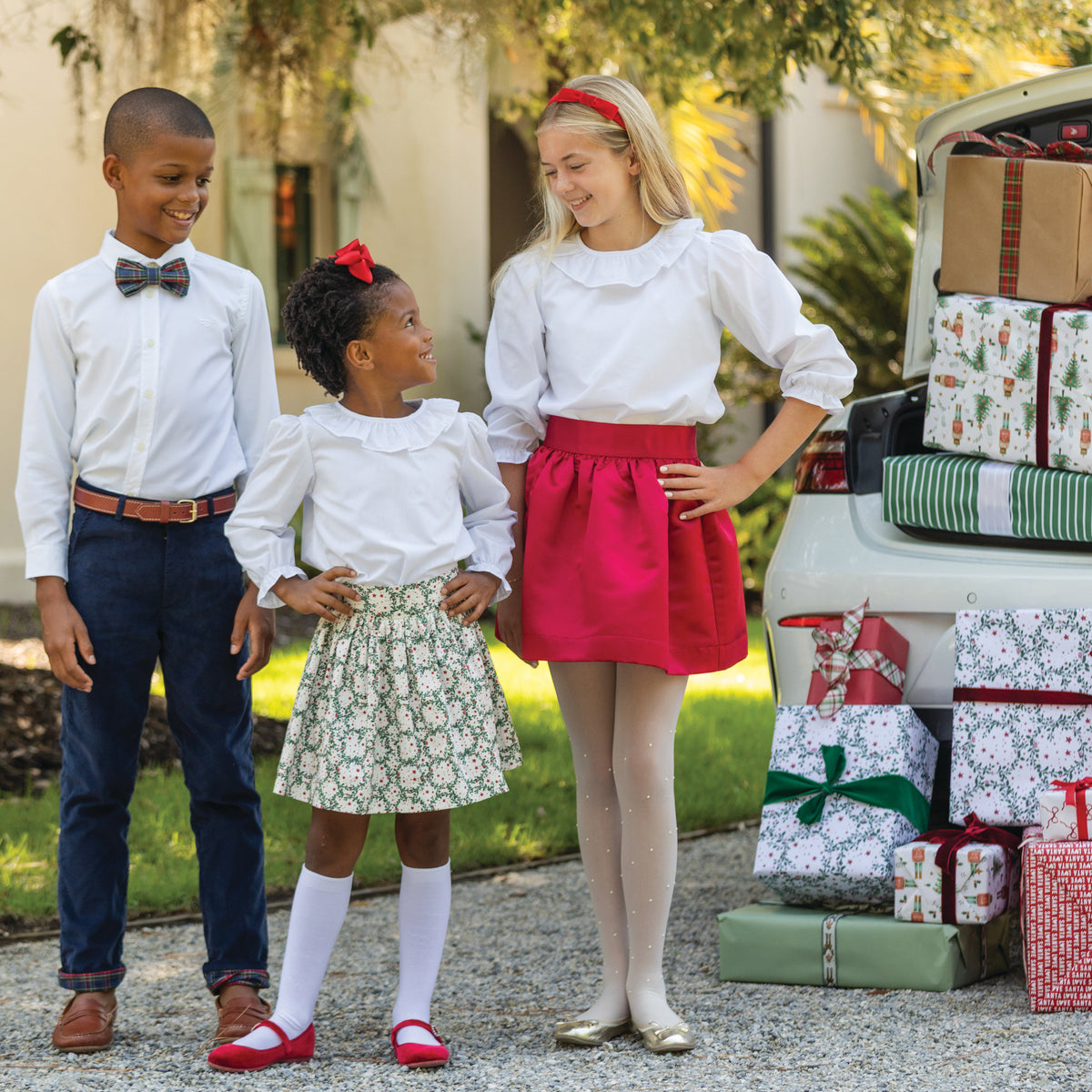 Girls’ Sutton Skirt in Regent Wreaths, featuring a festive green wreath and red star print on white with a full gathered silhouette.